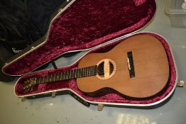 An unbranded electro acoustic guitar having Shadow sound hole pickup, in Hiscox plush lined case