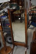 An early 20th Century frameless cheval mirror, having oak stand