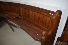 A traditional pitch pine pew, of curved form