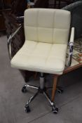A modern chrome frame and soft cream leather office chair, having the retro look