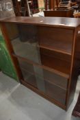 A vintage sapele bookcase having glass sliding doors, width approx. 91cm