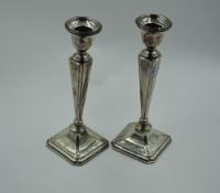 A pair of silver candlesticks of dainty form having plain tapered square columns and weighted square