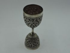 An Indian silver double ended spirit measure having extensive repousse floral and scroll decoration,