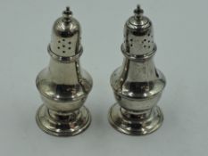 A pair of silver pepperettes of waisted baluster form having push on lids, Chester 1919, Stokes &