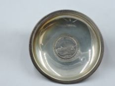 A German white metal trinket dish stamped 900 having bun feet and containing inset German coin dated