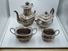A silver four piece tea set having gadrooned decoration with monogram to side, hard wood handles,