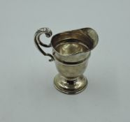 A small silver cream jug of helmet form having raised moulded loop handle and pedestal foot, Chester