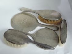 Five HM silver backed hand mirrors and brushes having engine turned decoration, AF