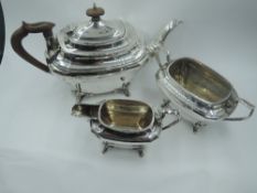 A silver three piece tea set of tapered and canted oval form having soft wood handles and bracket