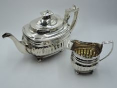 A Georgian silver teapot and sugar bowl of waisted oval form having fluted decoration, bun feet