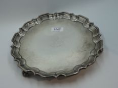 A Victorian silver salver having pie crust rim, worn crest to centre and trefoil acanthus leaf feet,