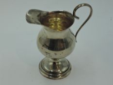 An Edwardian silver cream jug of helmet form on a circular pedestal foot, Birmingham 1904, Fattorini