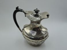 A silver hot water jug of baluster form having hard wood loop handle and facetted decoration, London