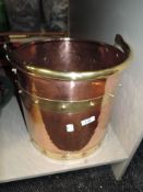 An arts and crafts style coal bucket having brass band and handle on hammered copper body