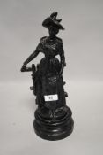 A late 19th century cast spelter figurine of a lady in traditional dress,hat and shawl by fence