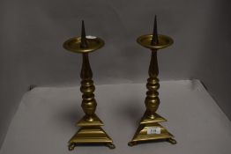 A pair of 17th century style brass pricket candlesticks, having iron spikes over the circular drip
