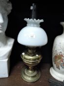A brass based oil lamp having a milk glass shade