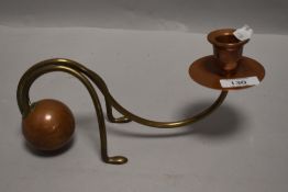 An unusual copper and brass candlestick, the weighted spherical base issuing two brass supports