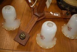 A vintage oak ceiling light fitting, three branch with opaque shades
