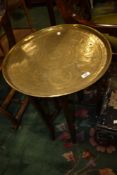 An Indian brass top table having folding wood frame
