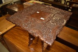 A carved occasional table having foldaway legs , intricate foliate carving to top , approx 49cm x