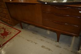A vintage teak sideboard having three drawers and double cupboard on stylised legs, probably 1970s