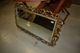 A reproduction gilt effect wall mirror having foliate frame