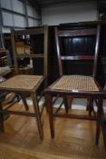 A pair of Edwardian mahogany bedroom chairs having cane seats