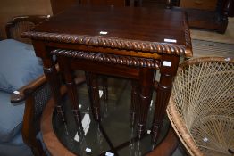 A reproduction mahogany effect nest of three tables in the classical style