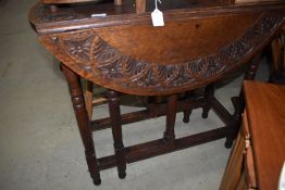 A late 19th or early 20th Century oak drop leaf table having carved top and turned frame