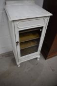 An early 20th Century glazed music or bijouterie cabinet, later painted