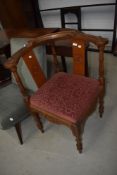 A traditional corner chair having heavy carved frame