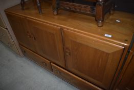 An Ercol mid colour sideboard, three cupboard over two drawers, on shepherds castors
