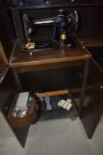 A vintage sewing machine in oak cabinet, with accesories etc