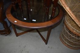 A vintage coffee table, circular dark teak and glass, labelled McIntosh