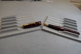 A Burnham leverfil fountain pen in Pink/Red and gold with single band to the cap having a Burnham