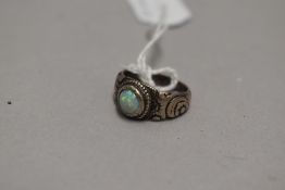 A white metal band ring having a matt white opal in a collared mount with moulded shoulders, no