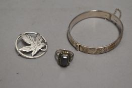 An HM silver hinged bangle having engraved foliate decoration, white metal leaf brooch stamped