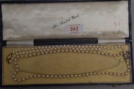 A knotted string of cultured pearls of even form having circular yellow metal box clasp stamped 333,