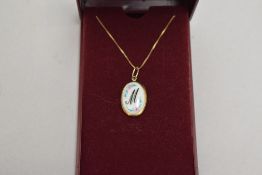 A ceramic pendant for initial M in a yellow metal mount on a 9ct gold box chain, approx 2.6g
