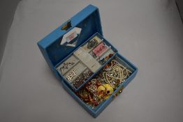 A small jewellery box containing a small selection of costume jewellery including brooches and