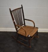 A late Victorian arts and crafts child's rocking chair, having spindle back with woven fibre seat,