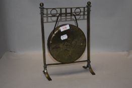 A small brass table-top dinner gong, lacking beater, the stand appears to have age.