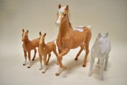 A matt white Beswick foal,a brown gloss Beswick horse and two Royal Doulton brown gloss foals.