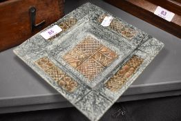 A Troika square dish in greens and browns, having incised abstract design, signed to base.