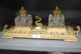 An ornate Victorian brass desk tidy having handles to sides,two cut glass ink wells and sea