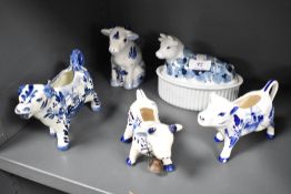 A collection of Delft ware cows including jugs and butter dish.