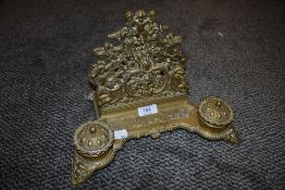 An ormolu ink pot and letter rack desk top tidy having foliate and cherub design