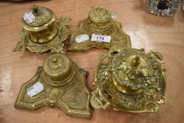 Four ornate brass cast ink wells having scroll and floral regency designs