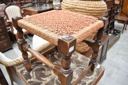 An early 20th century string-seated stool, with block and turned supports